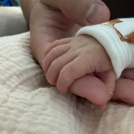 Danny Gonzalez holding hand of his just born baby.